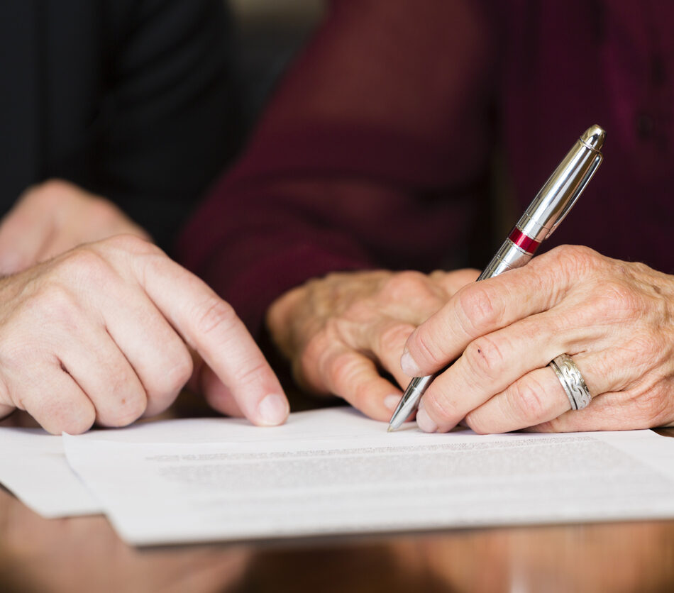 A senior citizen signing a document.