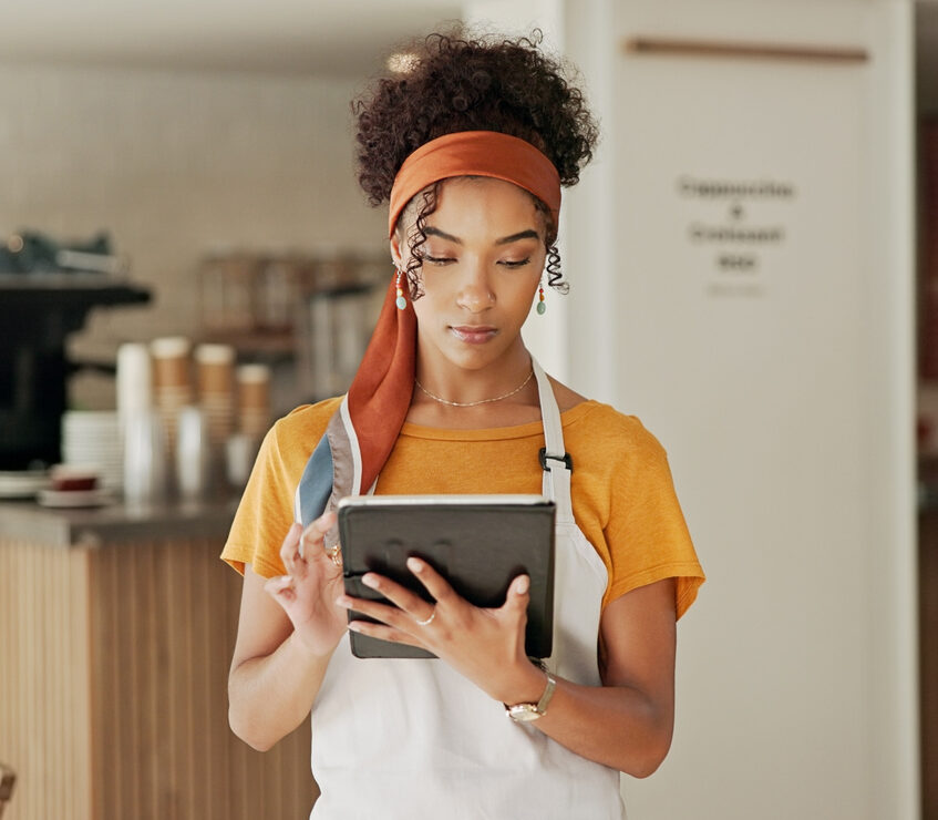 Cafe, woman and online with tablet for small business, menu planning and inventory management. Coffee shop, female manager and barista with digital for promotion, website or scroll orders for service