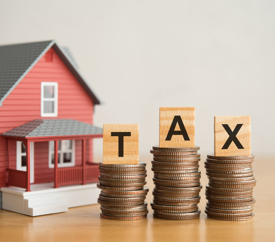 House and TAX alphabet on stack coins with white wall background. House, home, real estate property and land tax, taxation for home buying or selling, financial management concept.