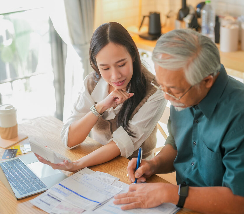 asian family home finance attractive young woman assisting her elderly father with her finances at home woman sitting and explaining financial documents to her dad in their home