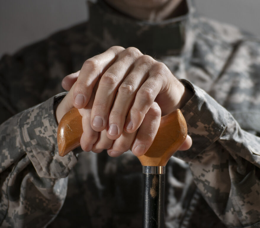 Soldier in camouflage uniform holding a cane, symbolizing veteran support and resilience